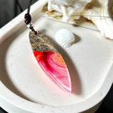 Aurora Flame – fluoreszierender Surfbrett-Anhänger aus Maserholz und leuchtendem Epoxidharz in Rosa, Pink, Orange und Weiß. Der handgefertigte Unikat-Anhänger fluoresziert bei Schwarzlicht in intensiven Farbtönen. Er ist ca. 6,3 x 2 cm groß, wird an einem verstellbaren Lederband (26–45 cm) getragen und ist mit einer silberfarbenen Spacerperle verziert. Ein ausdrucksstarkes Schmuckstück für Menschen mit Persönlichkeit.
