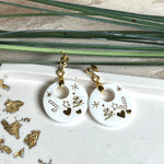 Handgefertigte Ohrringe aus weißem und klarem Harz mit goldenen Weihnachtsmotiven – Sterne, Herzen, Tannenbaum und Zuckerstange. Ohrstecker aus 925 Silber vergoldet, Anhängerschlaufe vergoldet. Größe ca. 37 mm × 25 mm. Leichte, elegante Festtagsohrringe mit warmem Goldglanz und winterlicher Ausstrahlung.