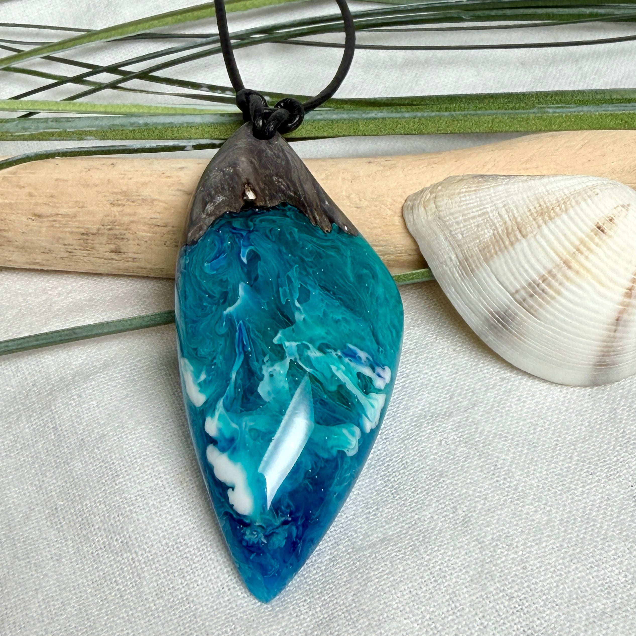 Anhänger aus dunklem Maserholz und Epoxidharz in Blau Türkis mit weißer Wellenstruktur am schwarzen Lederband, maritimer Holz Harz Naturschmuck unisex