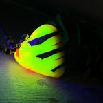 Herz-Anhänger aus Pinienzapfen & Harz, fluoreszierend bei Schwarzlicht. Farben Gelb-Orange-Weiß, Größe 4,2 × 3,8 cm. Lederband verstellbar.