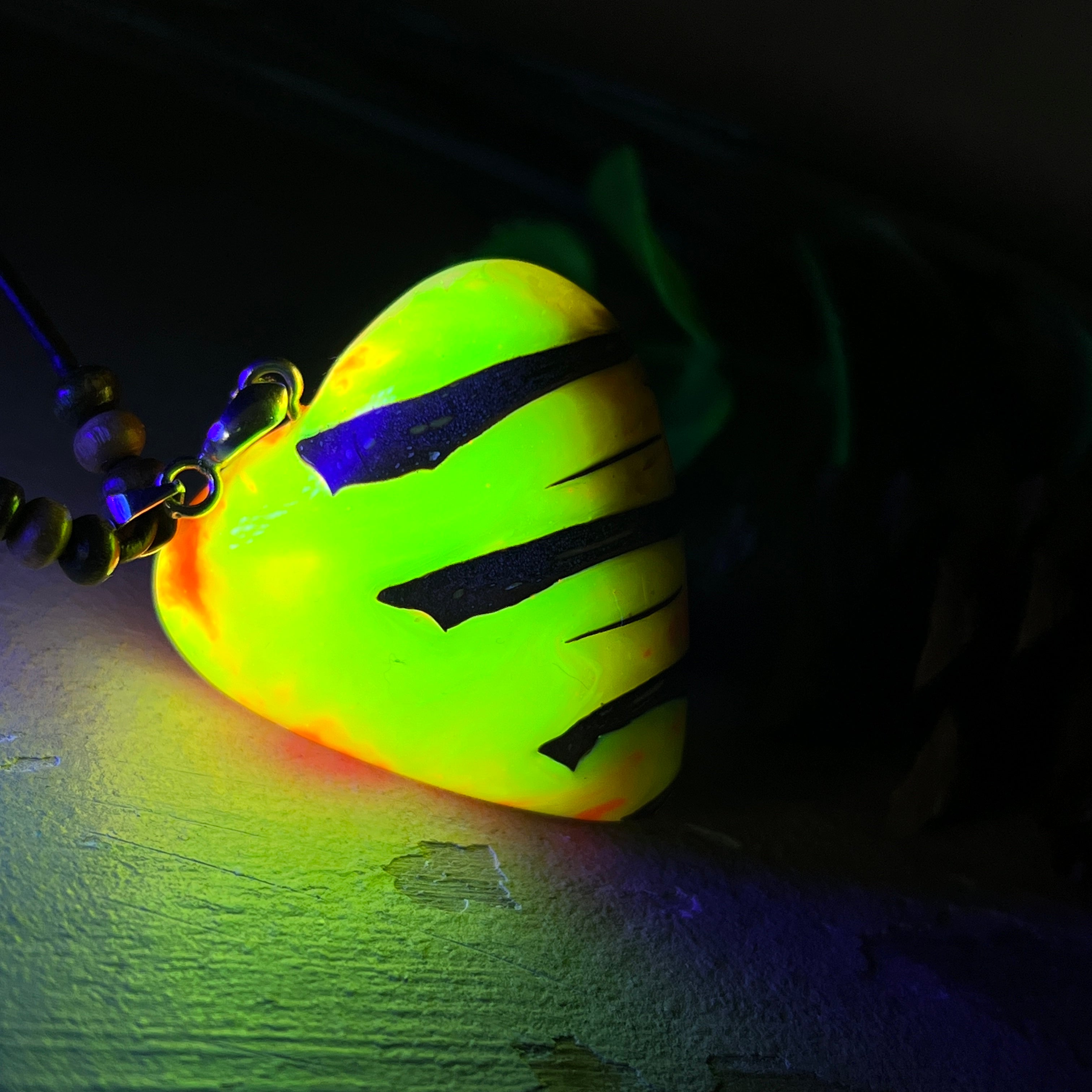 Herz-Anhänger aus Pinienzapfen & Harz, fluoreszierend bei Schwarzlicht. Farben Gelb-Orange-Weiß, Größe 4,2 × 3,8 cm. Lederband verstellbar.