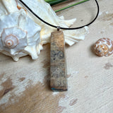 Rechteckiger Stabanhänger aus Maserholz und glasklarem Epoxidharz in tiefen Blau- und Türkistönen mit organischer Lagunen/Riff-Optik. Hochglanzpoliert, ca. 5,3 × 1,2 cm. Der Anhänger hängt an einer schwarzen Lederkette mit Edelstahl-Karabiner und 5-cm-Verlängerung (45 + 5 cm); die Anhängerschlaufe ist ebenfalls aus Edelstahl. Handgefertigtes Unikat, Lieferung in edler Schmuckbox – maritimer Look.