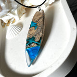 Handgefertigter Surfbrett-Anhänger aus Maserholz und transparentem Harz mit Farbverlauf in Blau und Weiß. Die natürliche Maserung des Holzes trifft auf ozeanartige Harzstrukturen. Größe ca. 6,7 x 2 cm, mit Edelstahlöse und Lederband inkl. Karabinerverschluss (45 cm + 5 cm Verlängerung). Jedes Stück ist ein Unikat – maritim, modern und mit viel Liebe gefertigt.
