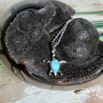 Feine Schildkröten-Kette aus rhodiniertem 925 Silber. Im Panzer des Anhängers liegt ein tropfenförmiger Larimar in hellem Blau. Der Anhänger ist ca. 22 x 18 mm groß und hängt an einer 45 cm langen, 1 mm starken Silberkette.