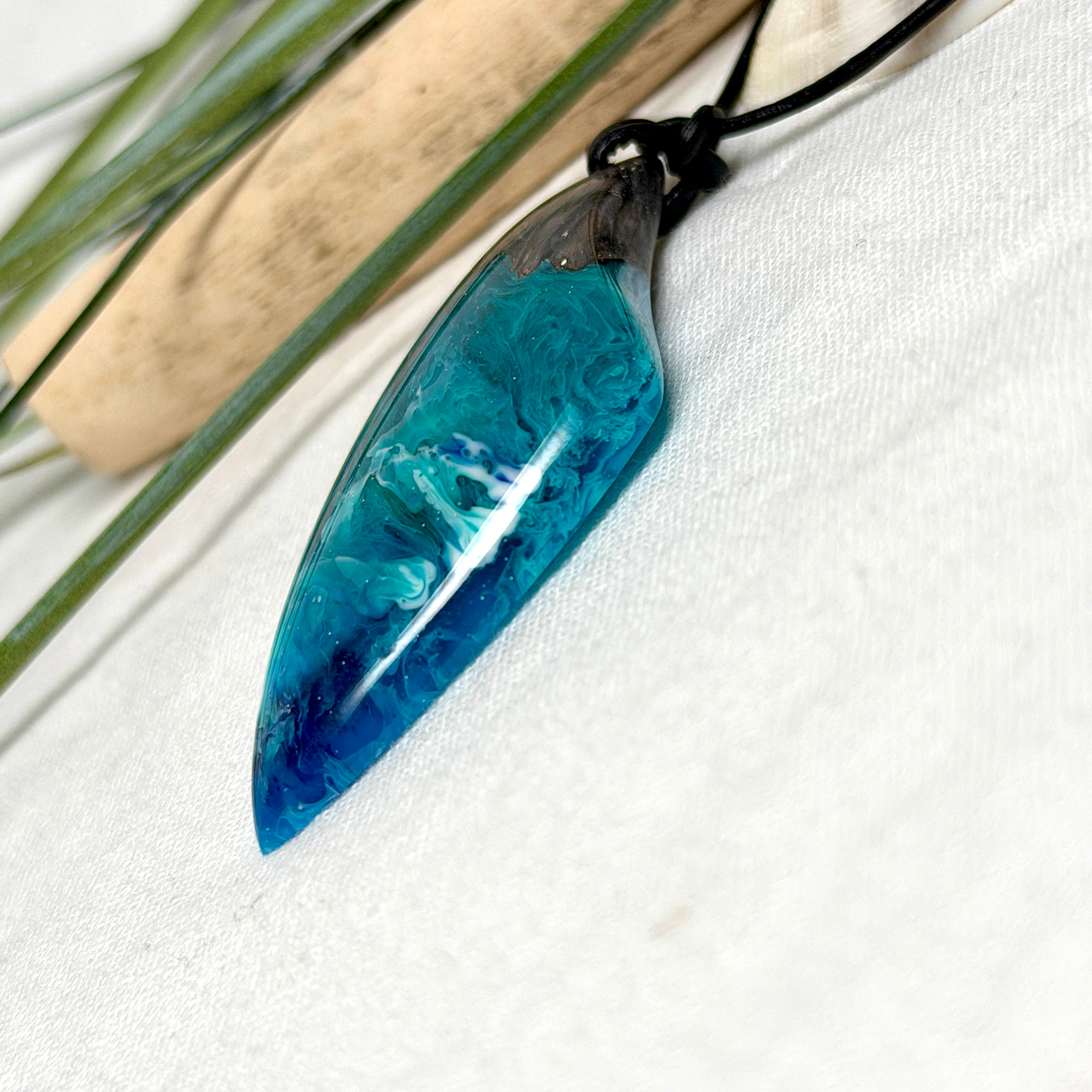 Anhänger aus dunklem Maserholz und Epoxidharz in Blau Türkis mit weißer Wellenstruktur am schwarzen Lederband, maritimer Holz Harz Naturschmuck unisex