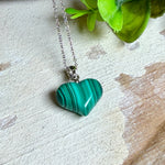 Halskette mit Malachit-Herz: kleiner, gewölbter Herzanhänger aus intensiv grün gebändertem Malachit, ca. 16 x 14 x 10 mm, in hochglanzpolierter, rhodinierter 925 Silberfassung an feiner Ankerkette aus Silber.