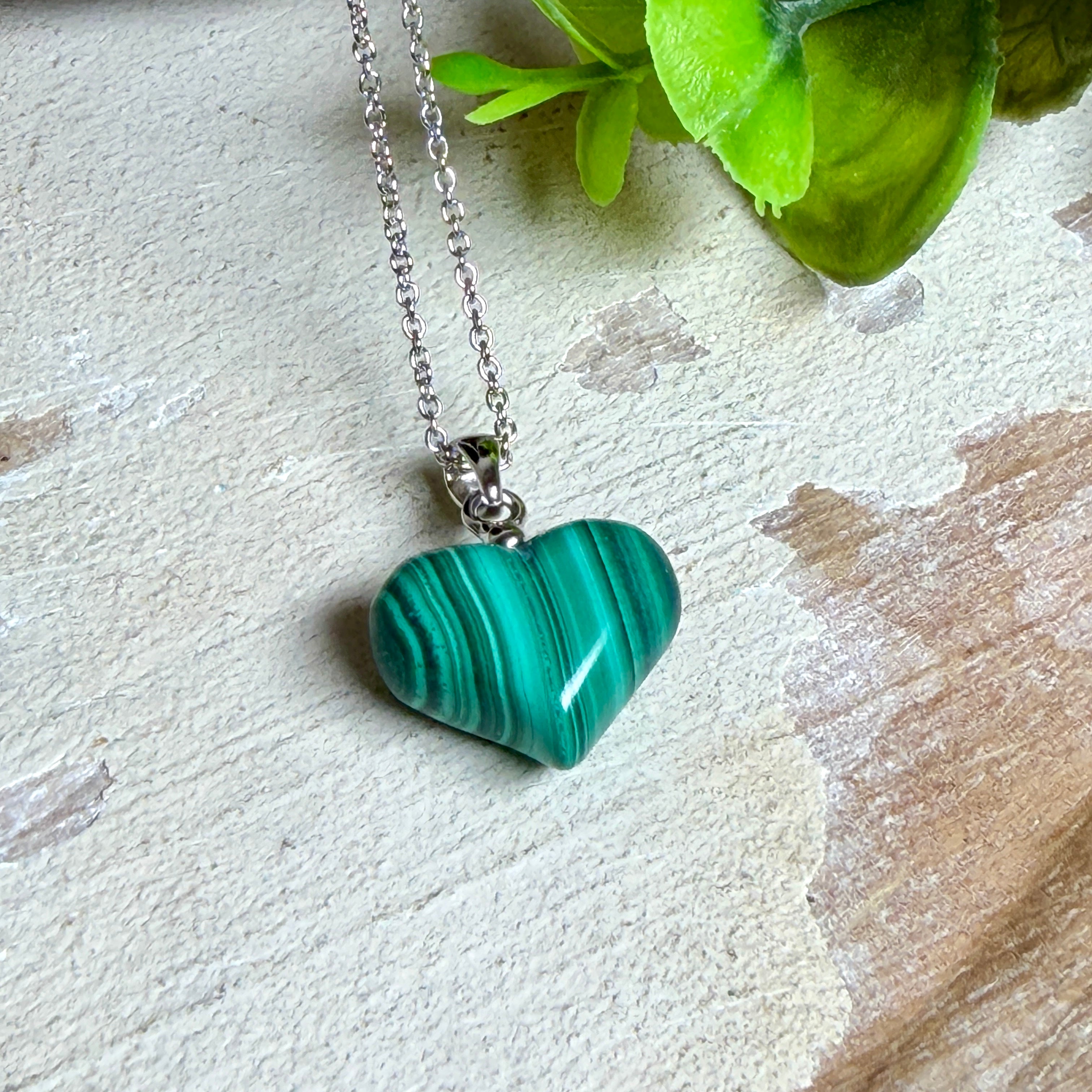 Halskette mit Malachit-Herz: kleiner, gewölbter Herzanhänger aus intensiv grün gebändertem Malachit, ca. 16 x 14 x 10 mm, in hochglanzpolierter, rhodinierter 925 Silberfassung an feiner Ankerkette aus Silber.