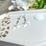 Edle „Ocean Star“ Ohrringe aus 925 Sterling Silber mit Seestern-Anhängern (18 × 17 mm), verziert mit einer aquablauen Apatitperle und funkelndem Zirkonia. Länge getragen: 45 mm. Maritime Schmuckstücke, die das Funkeln des Meeres einfangen – elegant, hochwertig und ein ideales Geschenk für Meeresliebhaber und Sommerträume.