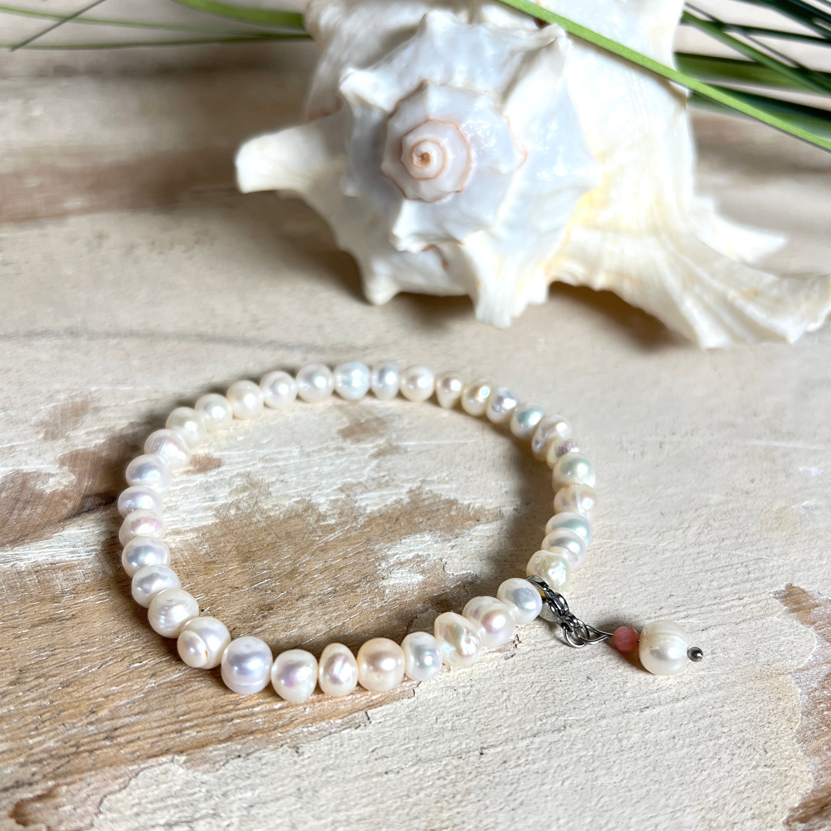 Handgefertigtes Armband „Ocean Bloom“ mit echten, schimmernden Süßwasserperlen (Ø ca. 6–7 mm) auf elastischem Band. Jede Perle ist ein Unikat mit natürlicher Form und sanftem Glanz. Highlight: Charmanhänger mit einer Süßwasserperle und einer facettierten Andenopal-Perle, befestigt an einem robusten Edelstahl-Karabiner. Ein Schmuckstück voller Eleganz, Symbolkraft und maritimer Schönheit.