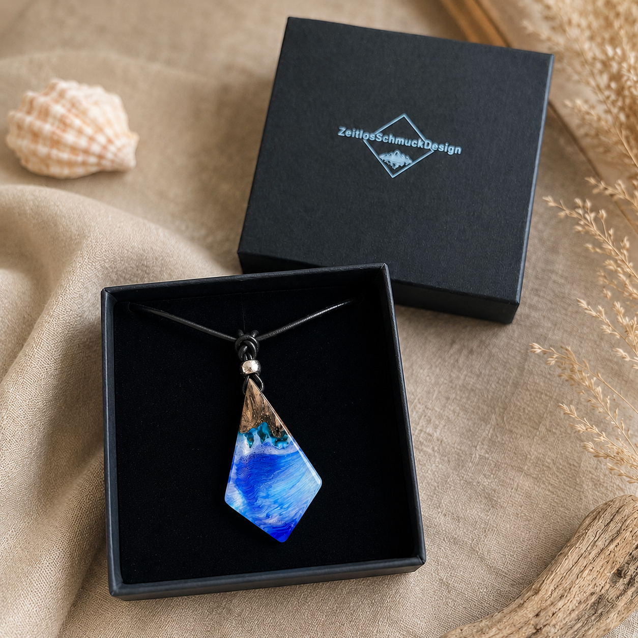 Schmuckbox-Bild WAVE WHISPER – handgefertigter Holz-Harz-Anhänger aus Maserholz und blau-weißem Epoxidharz, maritimer Naturschmuck am Lederband, präsentiert in schwarzer Schmuckbox von ZeitlosSchmuckDesign.