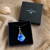 Schmuckbox-Bild WAVE WHISPER – handgefertigter Holz-Harz-Anhänger aus Maserholz und blau-weißem Epoxidharz, maritimer Naturschmuck am Lederband, präsentiert in schwarzer Schmuckbox von ZeitlosSchmuckDesign.