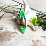 Anhänger aus Nussbaumholz und fluoreszierendem Epoxidharz in Grün-Weiß. Größe ca. 5,8 × 2 cm, Edelstahlöse, Lederkette 45+5 cm. Handgefertigtes Unikat.