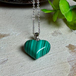 Halskette mit Malachit-Herz: kleiner, gewölbter Herzanhänger aus intensiv grün gebändertem Malachit, ca. 16 x 14 x 10 mm, in hochglanzpolierter, rhodinierter 925 Silberfassung an feiner Ankerkette aus Silber.