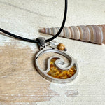 “Runder Wellenanhänger aus Edelstahl mit Bernstein-Harz-Inlay, Jaspisperle & facettiertem Bergkristall an schwarzer Lederkette (45 cm + 5 cm).”