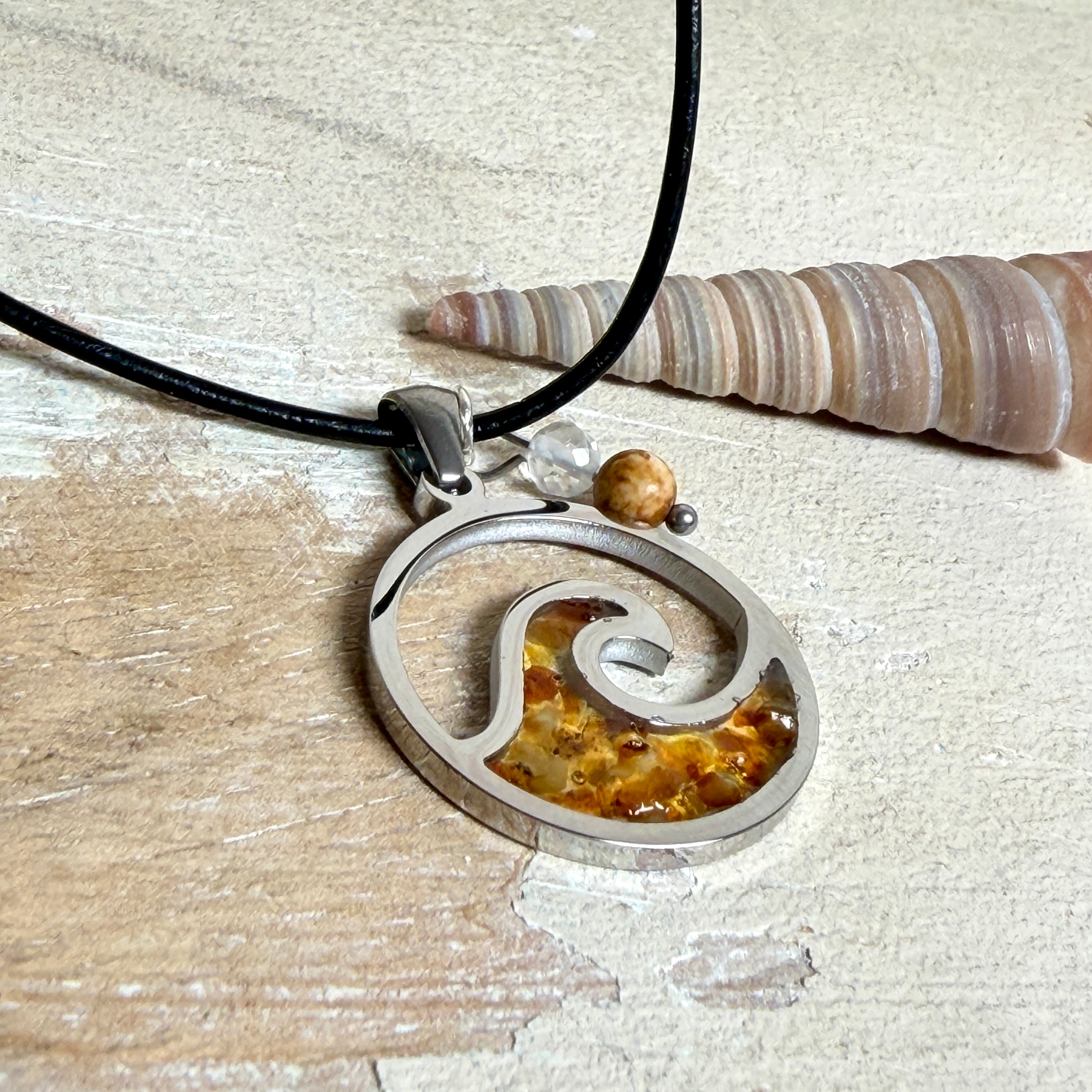 “Runder Wellenanhänger aus Edelstahl mit Bernstein-Harz-Inlay, Jaspisperle & facettiertem Bergkristall an schwarzer Lederkette (45 cm + 5 cm).”