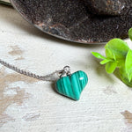 Halskette mit Malachit-Herz: kleiner, gewölbter Herzanhänger aus intensiv grün gebändertem Malachit, ca. 16 x 14 x 10 mm, in hochglanzpolierter, rhodinierter 925 Silberfassung an feiner Ankerkette aus Silber.