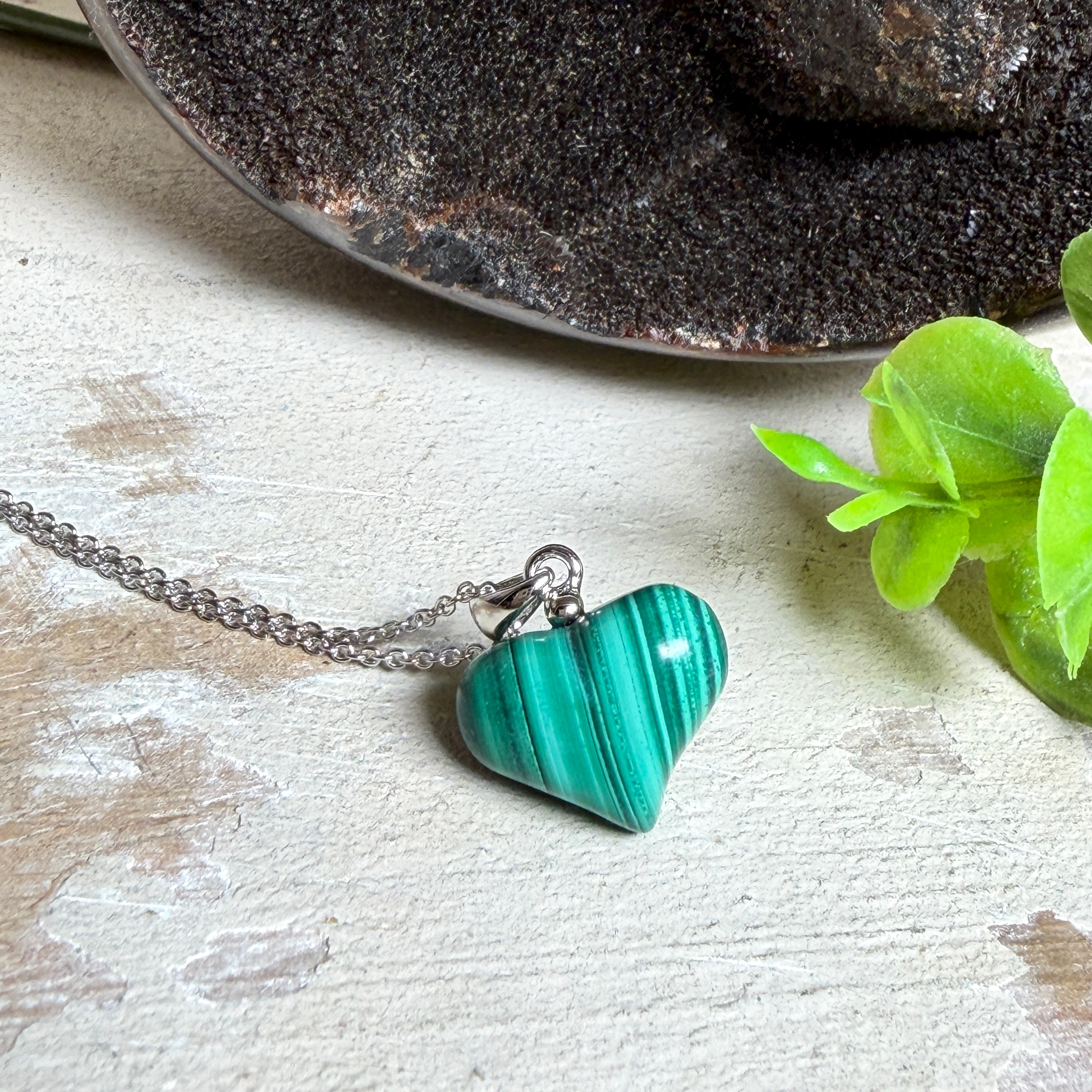 Halskette mit Malachit-Herz: kleiner, gewölbter Herzanhänger aus intensiv grün gebändertem Malachit, ca. 16 x 14 x 10 mm, in hochglanzpolierter, rhodinierter 925 Silberfassung an feiner Ankerkette aus Silber.