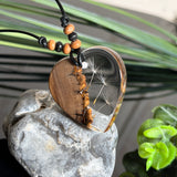 Handgefertigter Herzanhänger aus warm gemasertem Olivenholz und kristallklarem Epoxidharz mit schwebenden Pusteblumensamen. Schwarzes, verstellbares Lederband mit Schiebeknoten und naturfarbenen Holzperlen, Anhänger ca. 3,5 × 3,3 cm. Naturnaher Unikatschmuck von ZeitlosSchmuckDesign.