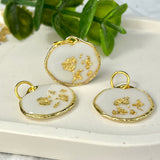 Gold-colored pendant with gold flakes, background in white and fluorescent under black light, birthday, gift