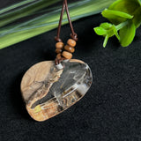 Handgefertigter Herzanhänger aus Olivenholz und klarem Harz mit echten Pusteblumen. Der Anhänger misst ca. 3,5 cm, das Lederband ist verstellbar von 23–43 cm und mit kleinen Holzperlen verziert. Ein natürliches Unikat, Symbol für Wünsche und Glück – sorgfältig gegossen, gesägt, geschliffen und poliert.