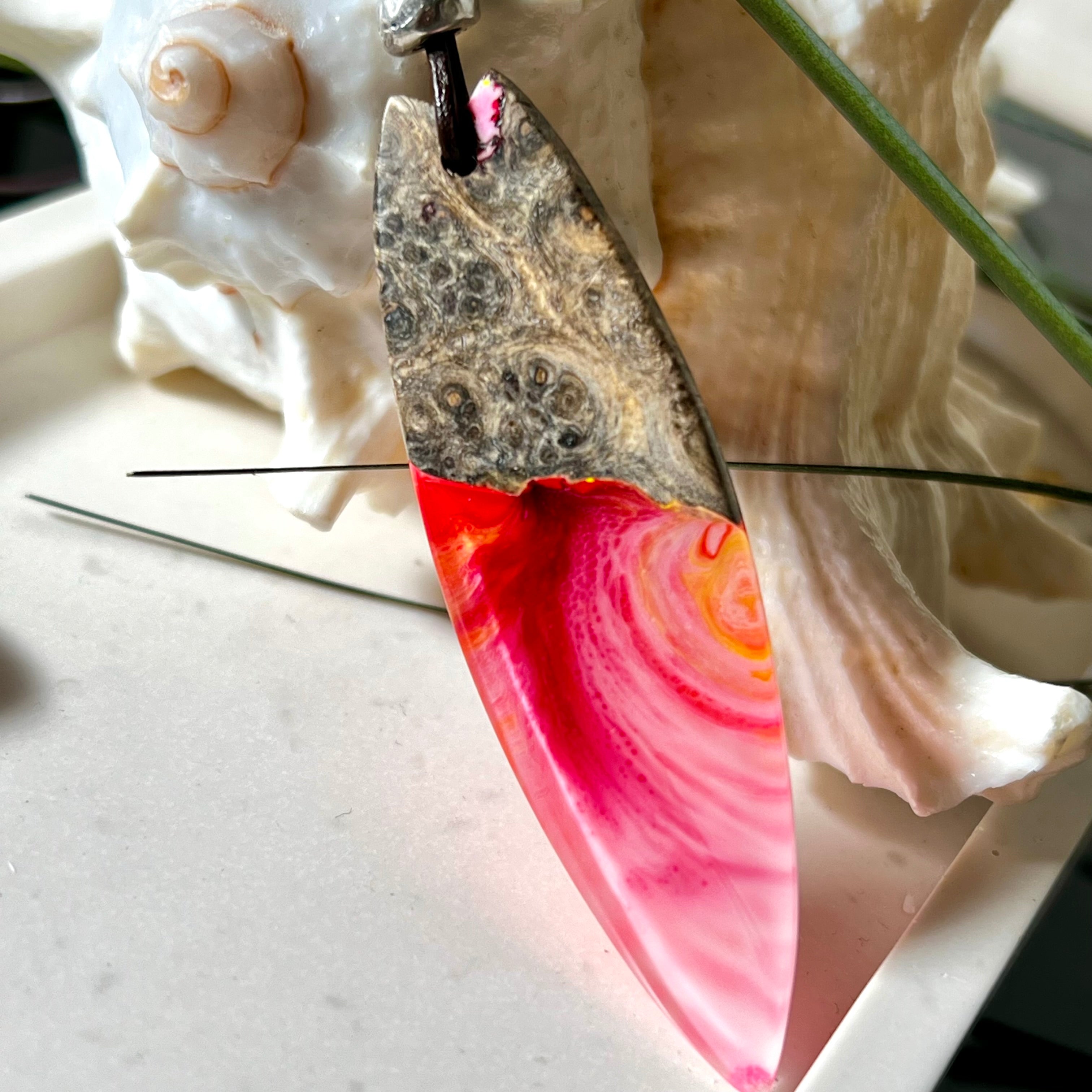 Aurora Flame – fluoreszierender Surfbrett-Anhänger aus Maserholz und leuchtendem Epoxidharz in Rosa, Pink, Orange und Weiß. Der handgefertigte Unikat-Anhänger fluoresziert bei Schwarzlicht in intensiven Farbtönen. Er ist ca. 6,3 x 2 cm groß, wird an einem verstellbaren Lederband (26–45 cm) getragen und ist mit einer silberfarbenen Spacerperle verziert. Ein ausdrucksstarkes Schmuckstück für Menschen mit Persönlichkeit.