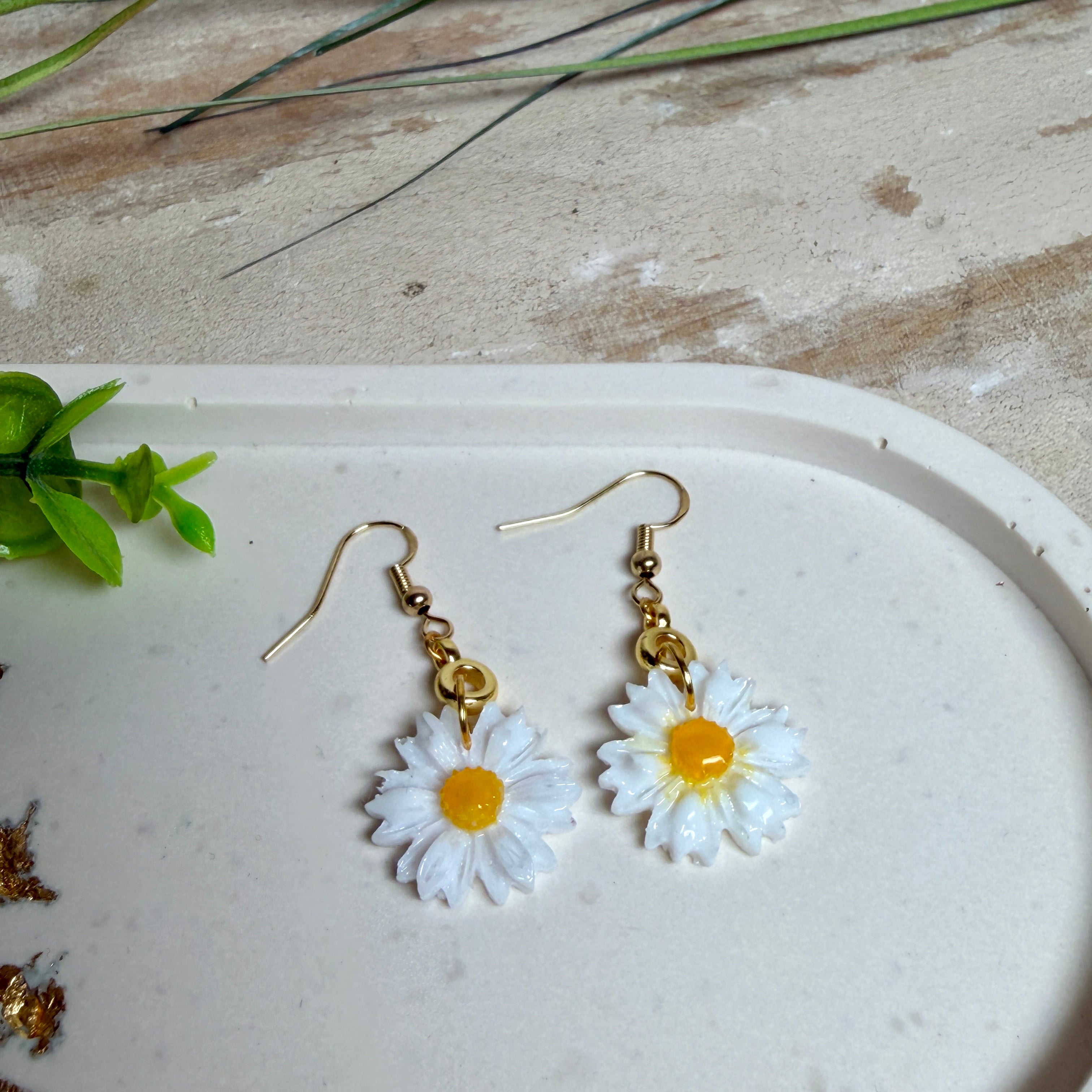 Handgefertigte Gänseblümchen-Ohrringe aus Harz mit 925 vergoldeten Ohrhaken, weiße Blüte mit gelbem Zentrum, goldfarbene Details, Länge ca. 4,5 cm.