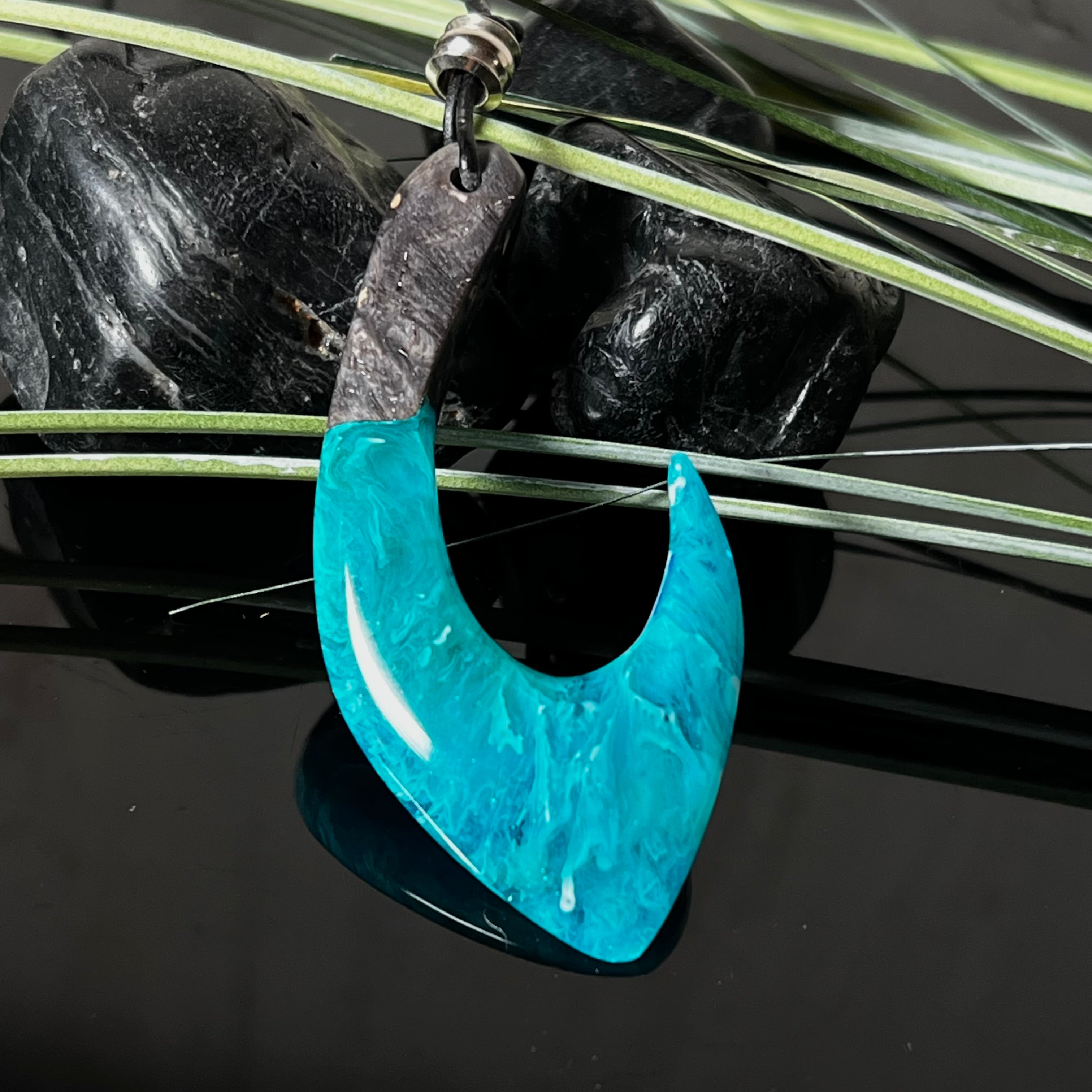 Handgefertigter Maori-Anhänger „Tangaroa Spirit“ in traditioneller Hakenform, gefertigt aus stabilisiertem Maserholz und ozeanblauem Harz. Die polierte Oberfläche bringt die natürlichen Maserungen und das tiefblaue Farbspiel besonders zur Geltung. Symbolisiert Schutz, Stärke und die Verbundenheit zum Meer. Verstellbares Lederband mit Schiebeknoten und dekorativen Holz- sowie Metallperlen – ideal als kraftvoller Talisman oder Geschenk.