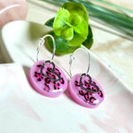 Handgemachte Leo-Creolen aus 925 Silber: Silber-Creolen 16 mm mit rosa Harz-Scheibe (2 cm) im Leoparden-Look und Edelstahl-Herzanhänger. Hängende Ohrringe in Animal-Print Stil, Gesamtlänge ca. 3,5 cm. Resin-Ohrringe für Alltag, Party oder Festival, femininer Statement-Schmuck in Rosa/Pink mit silberfarbenen Metallteilen. Einzeln gegossen, jedes Paar ein Unikat; leichte Abweichungen im Muster, Farbspiel und kleine Luftbläschen sind möglich und typisch für Handarbeit.