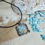 Quadratischer Larimar-Mosaik Anhänger im Edelstahlrahmen mit Seestern-Element und facettierter Bergkristall-Perle, eingebettet in Harz, an schwarzer Lederkette.