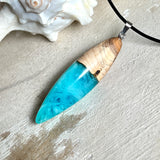 Anhänger aus Eibenholz und Epoxidharz in Blau-Türkis, Weiß und Transparent. Größe ca. 5,8 × 2 cm, Edelstahlöse, Lederkette 45+5 cm. Handgefertigtes Unikat inspiriert vom Ozean.