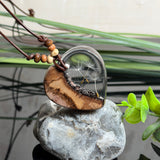 Herzanhänger „Pusteblumenzauber“ aus naturbelassenem Rebholz und klarem Epoxidharz mit schwebenden Pusteblumensamen. Dunkelbraunes, verstellbares Lederband mit kleinen Holzperlen, Anhänger ca. 3,5 × 3,5 cm. Handgefertigtes Unikat von ZeitlosSchmuckDesign.