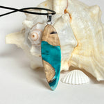 Handgefertigte Surfbrett Kette aus Maserholz und türkisfarbenem Resin mit Edelstahl Anhängerschlaufe an schwarzer Lederkette mit Karabiner und Verlängerung. Filigraner Ocean Anhänger inspiriert von Meer und Wellen, natürlicher Unikat Schmuck für Damen und Herren.
