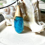Tropfenförmiger Anhänger aus Maserholz und Harz in leuchtenden Blautönen und Weiß. Inspiriert vom Meer, in Handarbeit gegossen,gesägt, geschliffen und hochglanzpoliert. Mit verstellbarer Lederkette (45 + 5 cm) und Edelstahlkarabiner. Jeder Anhänger ist ein Unikat mit natürlicher Maserung. Ein maritimes Schmuckstück für Naturfreunde und alle, die das Wasser lieben.