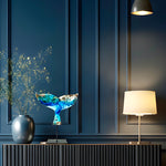 Handgefertigte Walflossen-Skulptur „Ocean Grace“ aus Maserholz und Epoxidharz in Blau, Weiß und Türkis, auf schwarzem Metallständer, ca. 29 x 27 cm, als exklusives maritimes Deko-Kunstwerk auf einem modernen Sideboard vor dunkler Wand platziert.