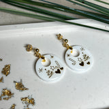 Handgefertigte Ohrringe aus weißem und klarem Harz mit goldenen Weihnachtsmotiven – Sterne, Herzen, Tannenbaum und Zuckerstange. Ohrstecker aus 925 Silber vergoldet, Anhängerschlaufe vergoldet. Größe ca. 37 mm × 25 mm. Leichte, elegante Festtagsohrringe mit warmem Goldglanz und winterlicher Ausstrahlung.