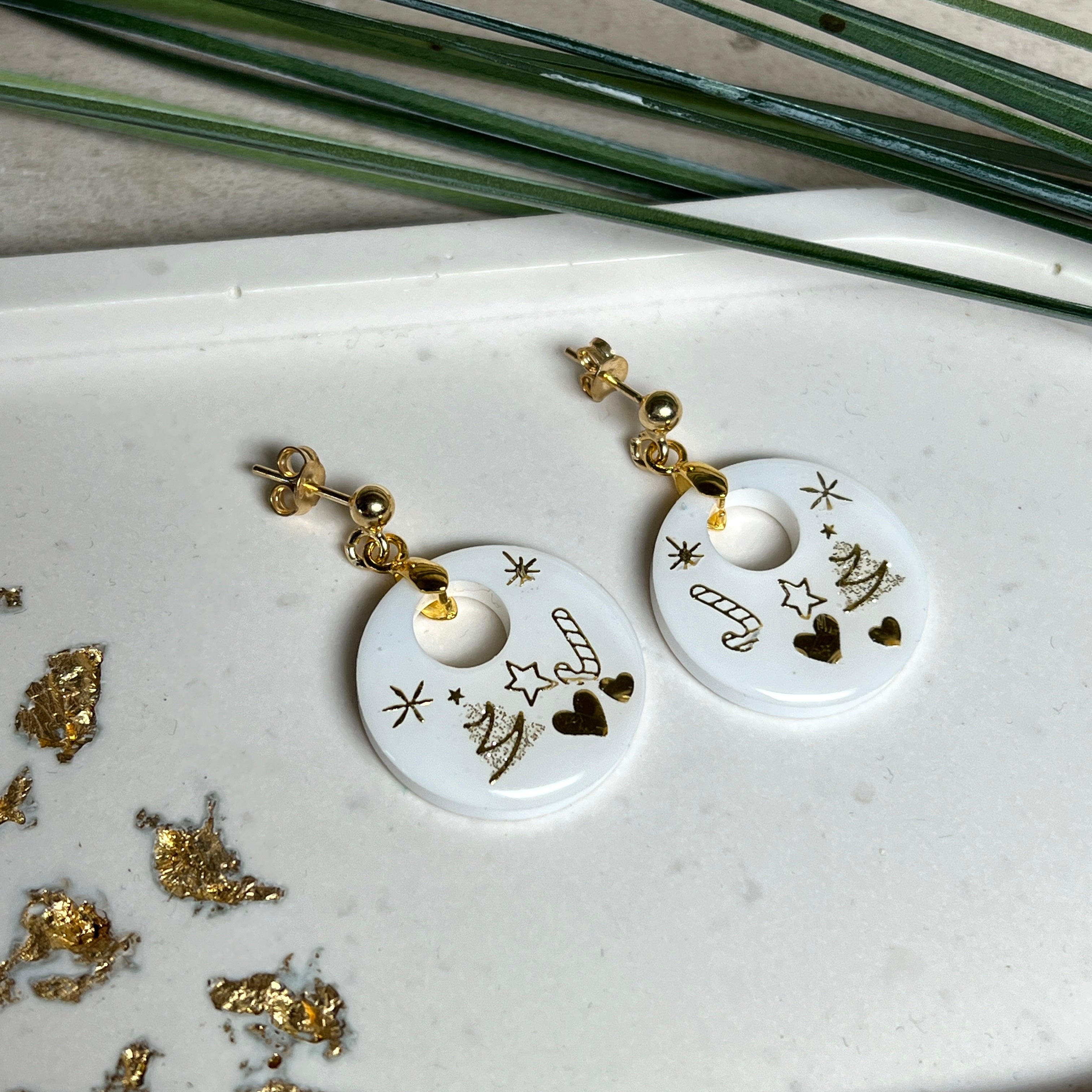Handgefertigte Ohrringe aus weißem und klarem Harz mit goldenen Weihnachtsmotiven – Sterne, Herzen, Tannenbaum und Zuckerstange. Ohrstecker aus 925 Silber vergoldet, Anhängerschlaufe vergoldet. Größe ca. 37 mm × 25 mm. Leichte, elegante Festtagsohrringe mit warmem Goldglanz und winterlicher Ausstrahlung.
