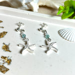 Edle „Ocean Star“ Ohrringe aus 925 Sterling Silber mit Seestern-Anhängern (18 × 17 mm), verziert mit einer aquablauen Apatitperle und funkelndem Zirkonia. Länge getragen: 45 mm. Maritime Schmuckstücke, die das Funkeln des Meeres einfangen – elegant, hochwertig und ein ideales Geschenk für Meeresliebhaber und Sommerträume.