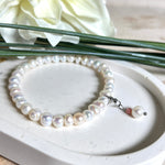 Handgefertigtes Armband „Ocean Bloom“ mit echten, schimmernden Süßwasserperlen (Ø ca. 6–7 mm) auf elastischem Band. Jede Perle ist ein Unikat mit natürlicher Form und sanftem Glanz. Highlight: Charmanhänger mit einer Süßwasserperle und einer facettierten Andenopal-Perle, befestigt an einem robusten Edelstahl-Karabiner. Ein Schmuckstück voller Eleganz, Symbolkraft und maritimer Schönheit.