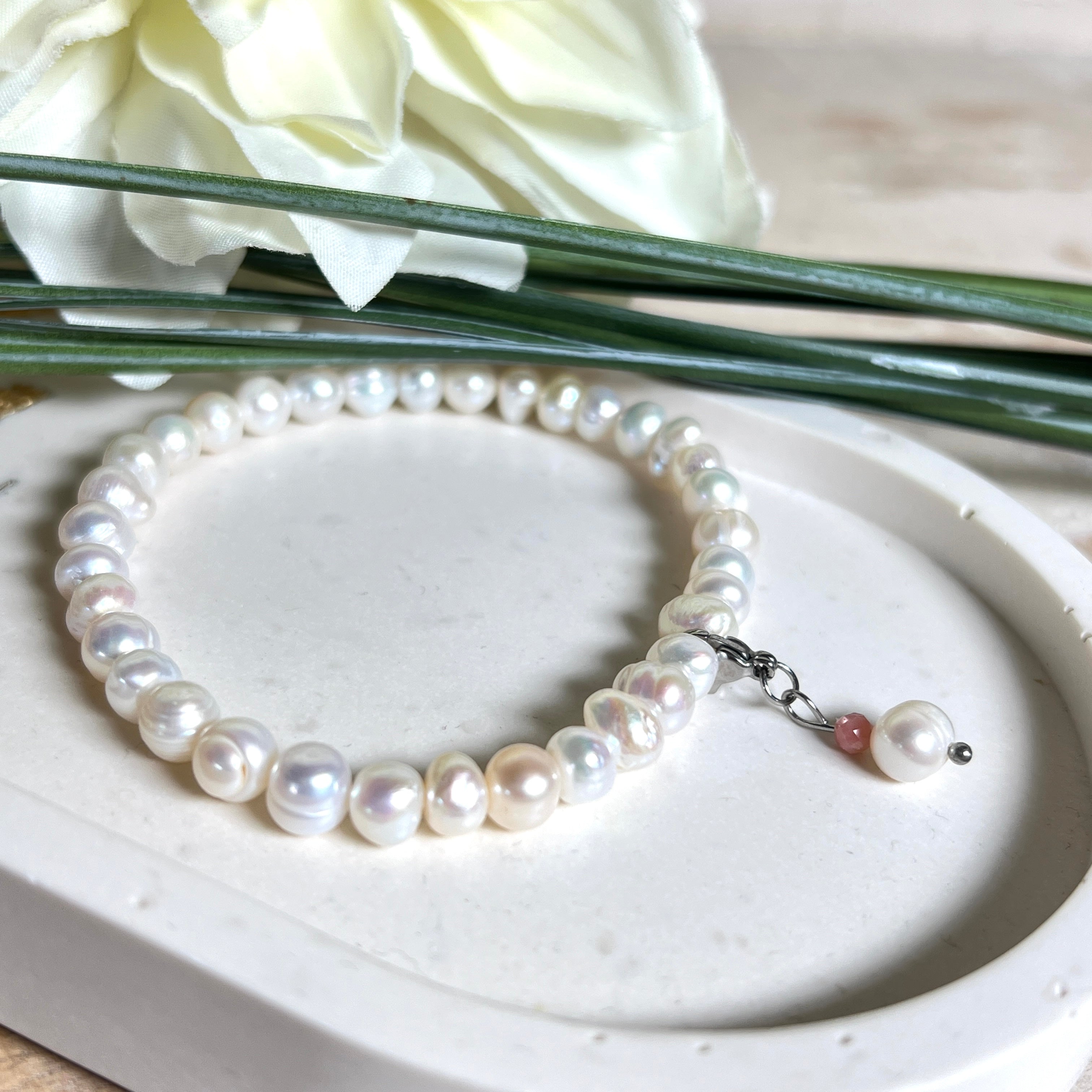 Handgefertigtes Armband „Ocean Bloom“ mit echten, schimmernden Süßwasserperlen (Ø ca. 6–7 mm) auf elastischem Band. Jede Perle ist ein Unikat mit natürlicher Form und sanftem Glanz. Highlight: Charmanhänger mit einer Süßwasserperle und einer facettierten Andenopal-Perle, befestigt an einem robusten Edelstahl-Karabiner. Ein Schmuckstück voller Eleganz, Symbolkraft und maritimer Schönheit.