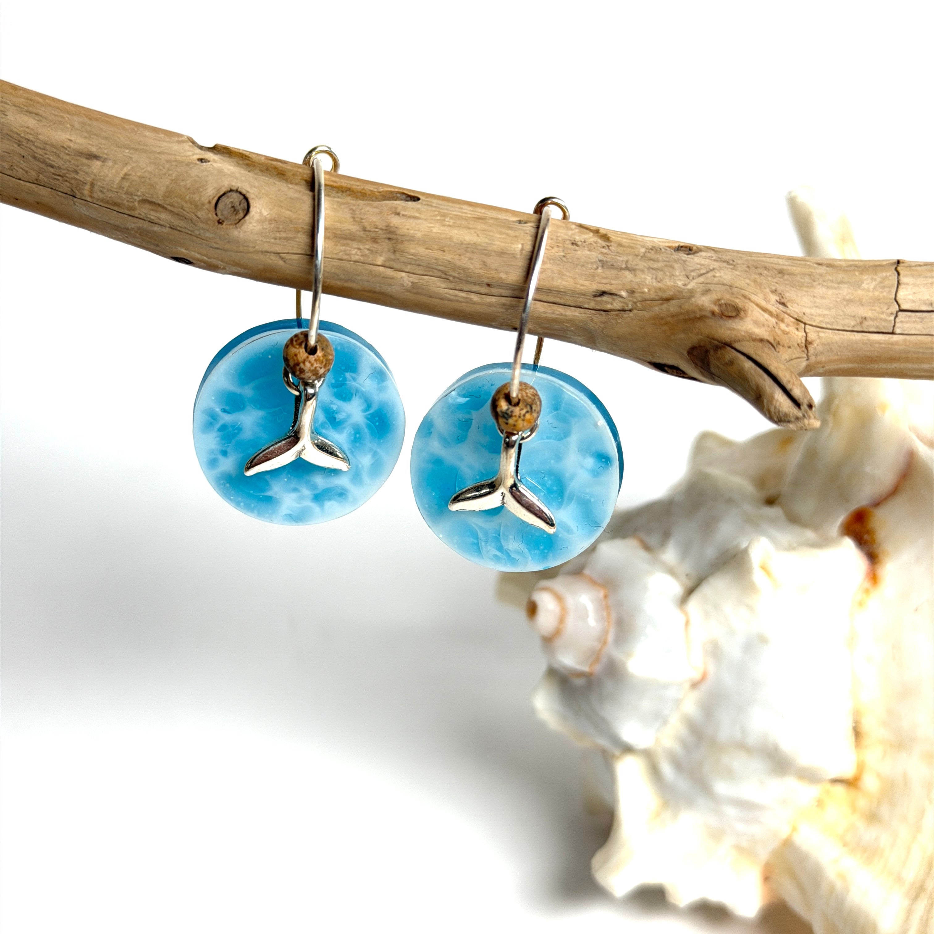 Handgefertigte Creolen-Ohrringe mit hellblauer Resin-Scheibe, zarter Wolkenmarmorierung, silbernem Walflosse-Charm und Jaspis-Natursteinperle. 925 Silber Creole, Gesamtlänge ca. 3,5 cm – Ocean-Feeling für jeden Tag.