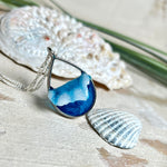 „Lagunenlicht“ – Tropfenanhänger mit handmodellierter 3D-Welle und feinem Glitzereffekt. Klarer Harzlook in Blau/Türkis, gefasst in Silber-Legierung. Größe ca. 3,5 × 2 cm. Geliefert an einer versilberten Kette (ca. 56 cm). Hochglänzend , maritimer Unikatcharakter.