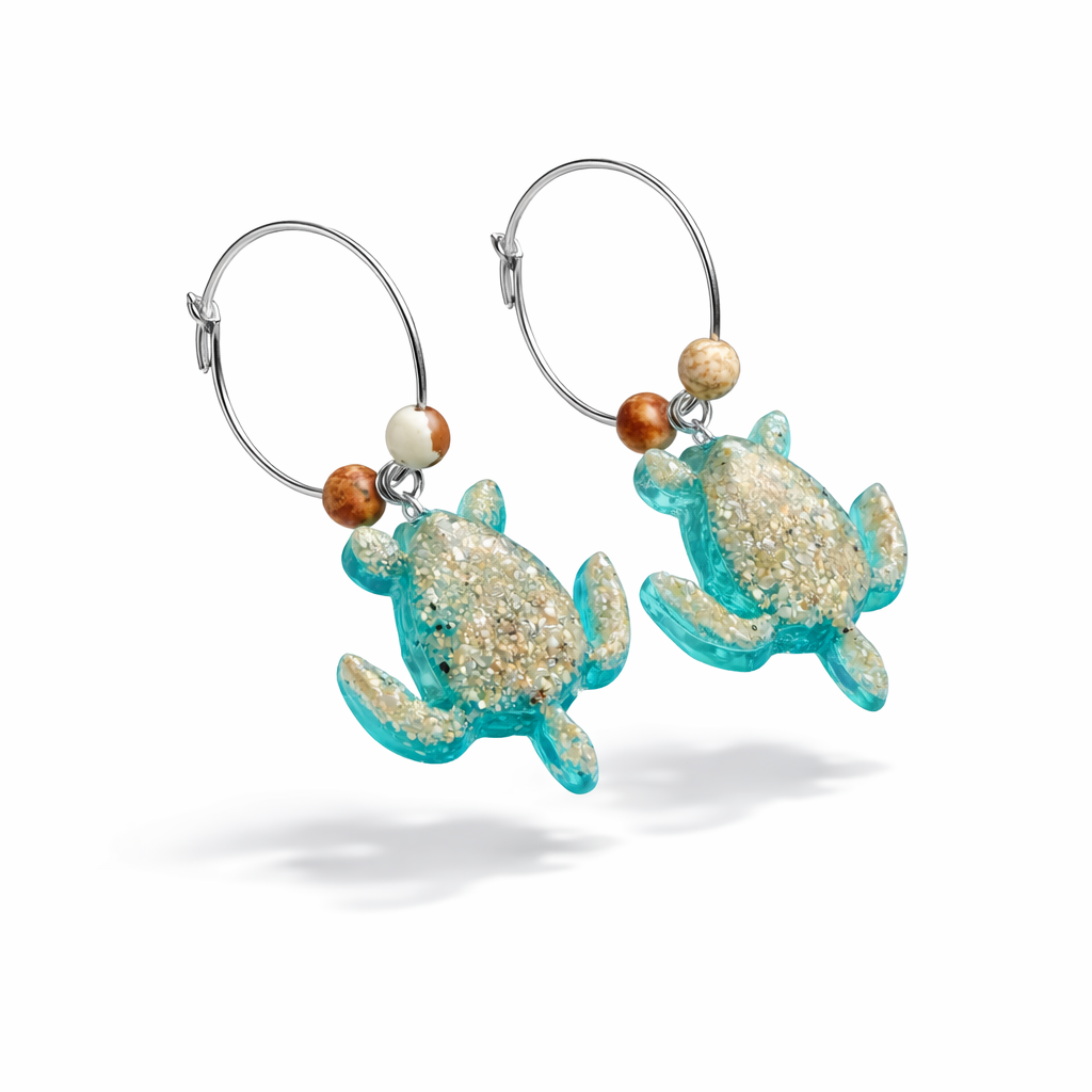 Türkisfarbene Schildkröten-Creolen an feinen 16-mm-Ringen aus 925 Silber, jeweils mit echtem Strandsand im Harz eingebettet und mit kleinen Jaspis-Edelsteinperlen verziert; handgefertigtes Unikat mit sommerlich-maritimem Look, fotografiert als Freisteller, Nahaufnahme oder auf dekorativem Untergrund.