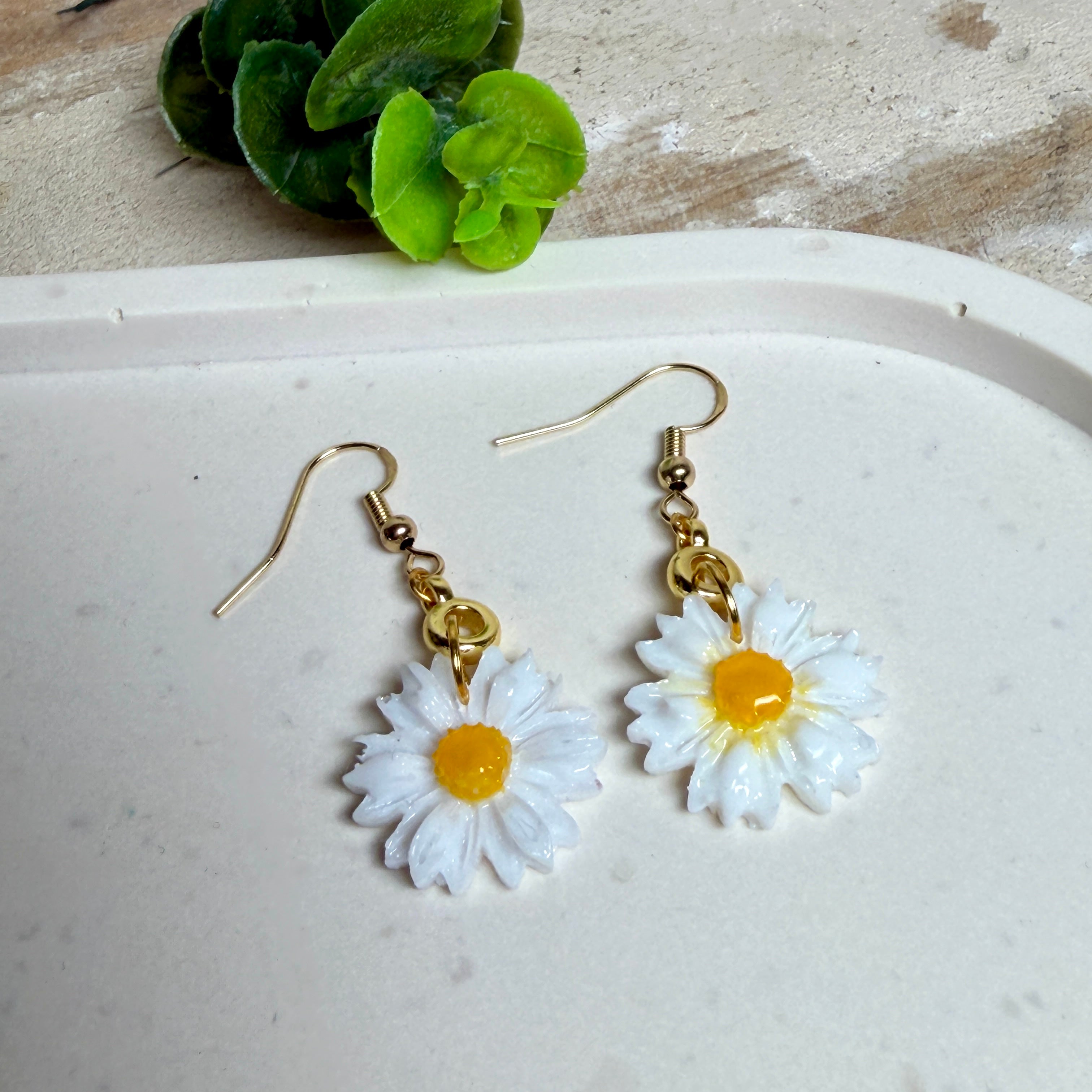 Handgefertigte Gänseblümchen-Ohrringe aus Harz mit 925 vergoldeten Ohrhaken, weiße Blüte mit gelbem Zentrum, goldfarbene Details, Länge ca. 4,5 cm.