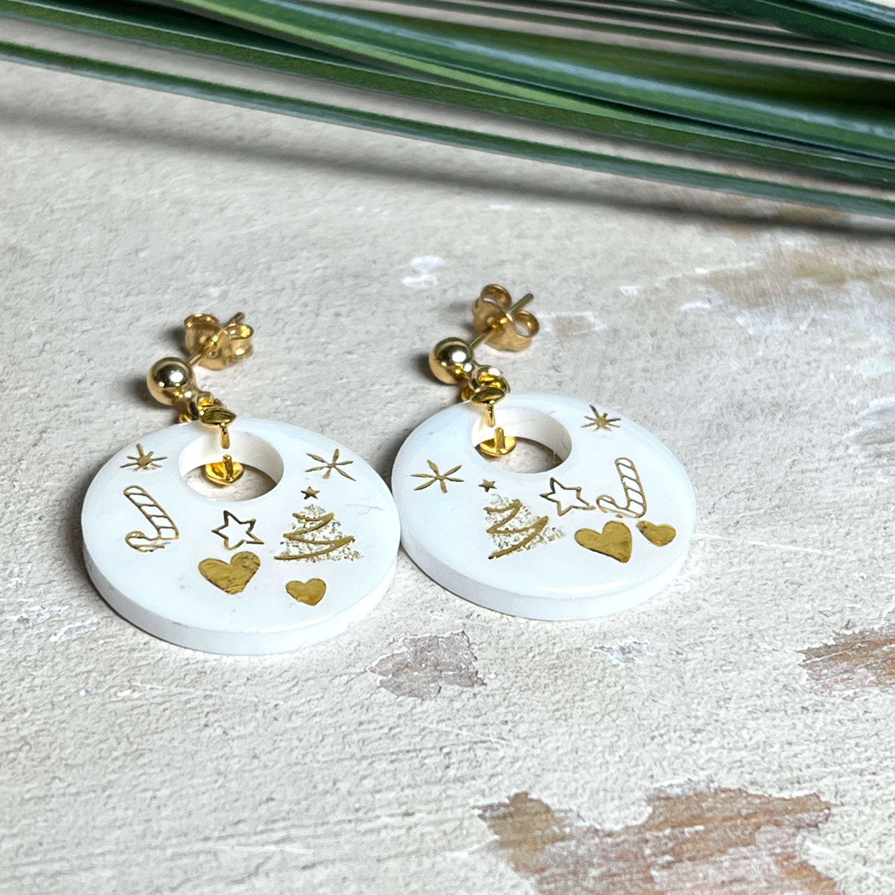 Handgefertigte Ohrringe aus weißem und klarem Harz mit goldenen Weihnachtsmotiven – Sterne, Herzen, Tannenbaum und Zuckerstange. Ohrstecker aus 925 Silber vergoldet, Anhängerschlaufe vergoldet. Größe ca. 37 mm × 25 mm. Leichte, elegante Festtagsohrringe mit warmem Goldglanz und winterlicher Ausstrahlung.