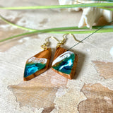 Handgefertigte Ohrringe „Ocean Diamond“ aus Olivenholz und Epoxidharz in Diamantform. Türkis-, Blau- und Weißtöne bilden ein wellenartiges Design, inspiriert vom Meer. Jeder Ohrring ist ein Unikat mit individueller Maserung. Vergoldete, nickelfreie und bleifreie Anhängerschlaufe, 925 Sterling Silber Ohrhaken. Maritimer Schmuck für Meerliebhaber und besondere Anlässe.