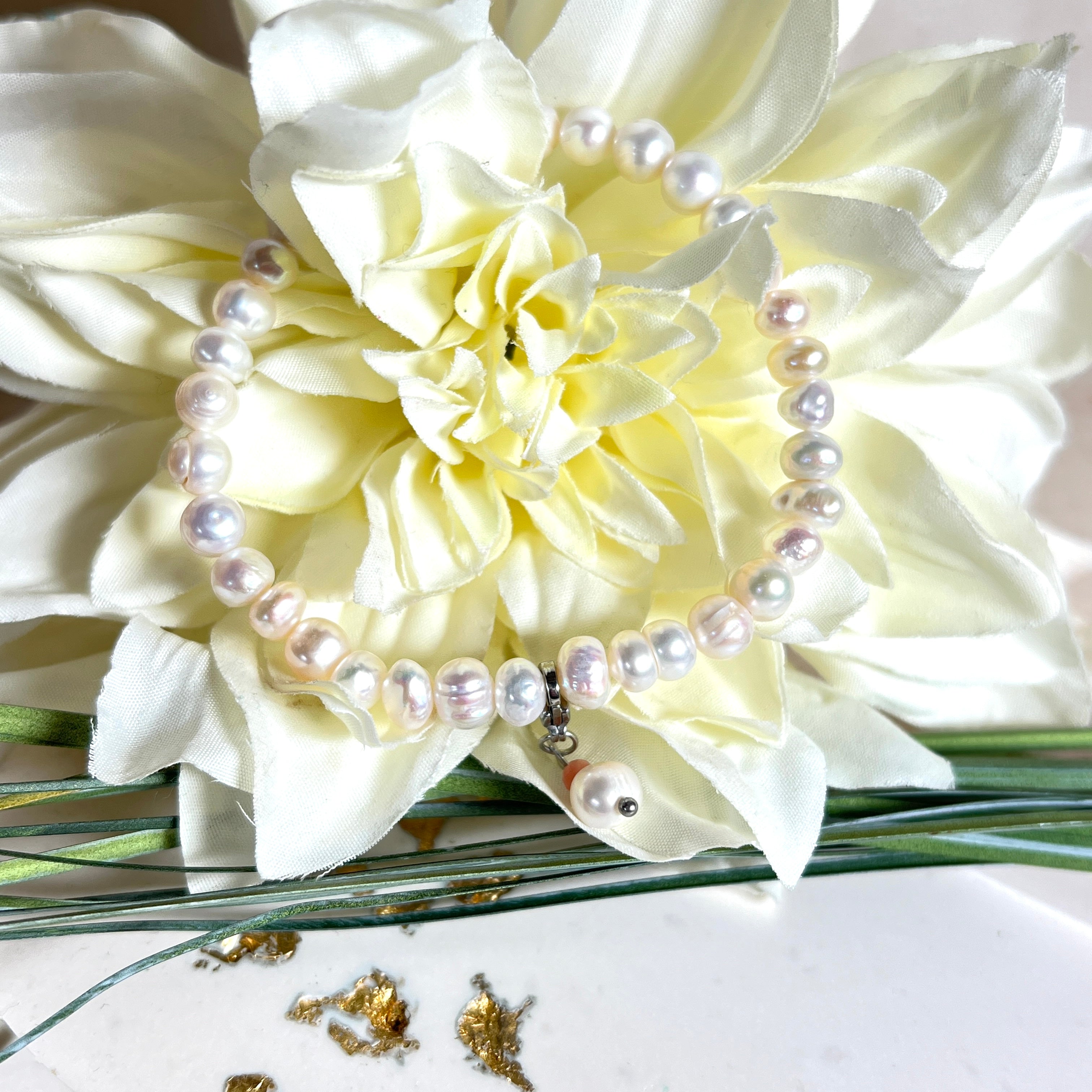 Handgefertigtes Armband „Ocean Bloom“ mit echten, schimmernden Süßwasserperlen (Ø ca. 6–7 mm) auf elastischem Band. Jede Perle ist ein Unikat mit natürlicher Form und sanftem Glanz. Highlight: Charmanhänger mit einer Süßwasserperle und einer facettierten Andenopal-Perle, befestigt an einem robusten Edelstahl-Karabiner. Ein Schmuckstück voller Eleganz, Symbolkraft und maritimer Schönheit.