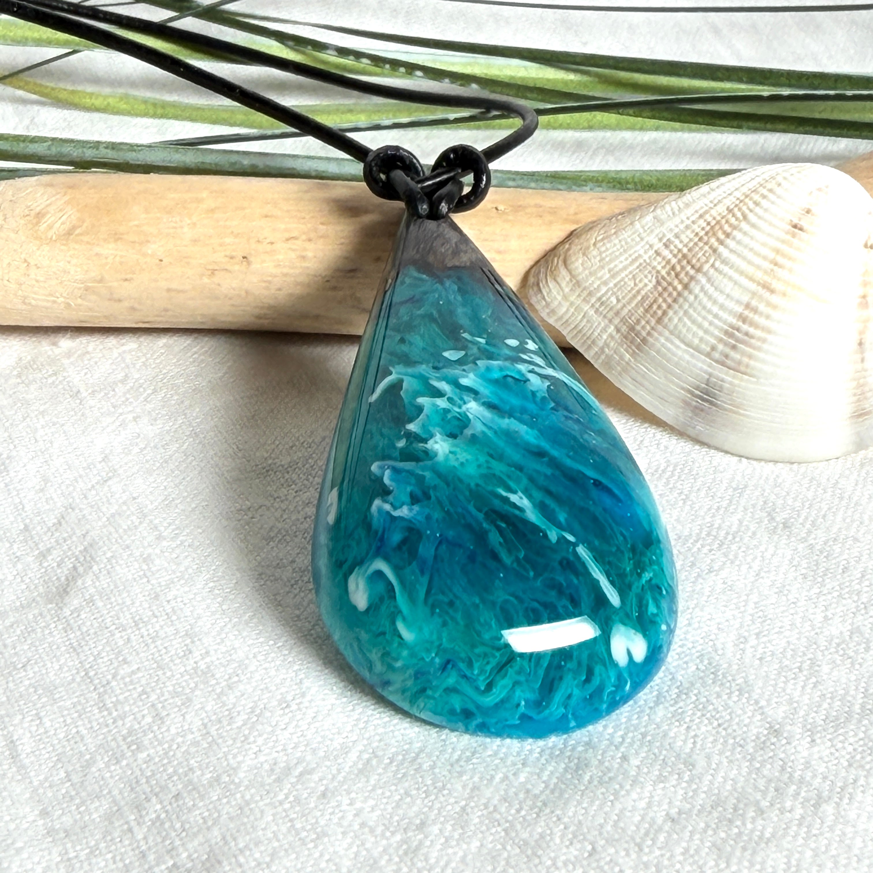 Tropfen Anhänger aus dunklem Maserholz und Epoxidharz in Türkis Blau mit weißer Wellenstruktur am schwarzen Lederband, maritimer Holz Harz Naturschmuck