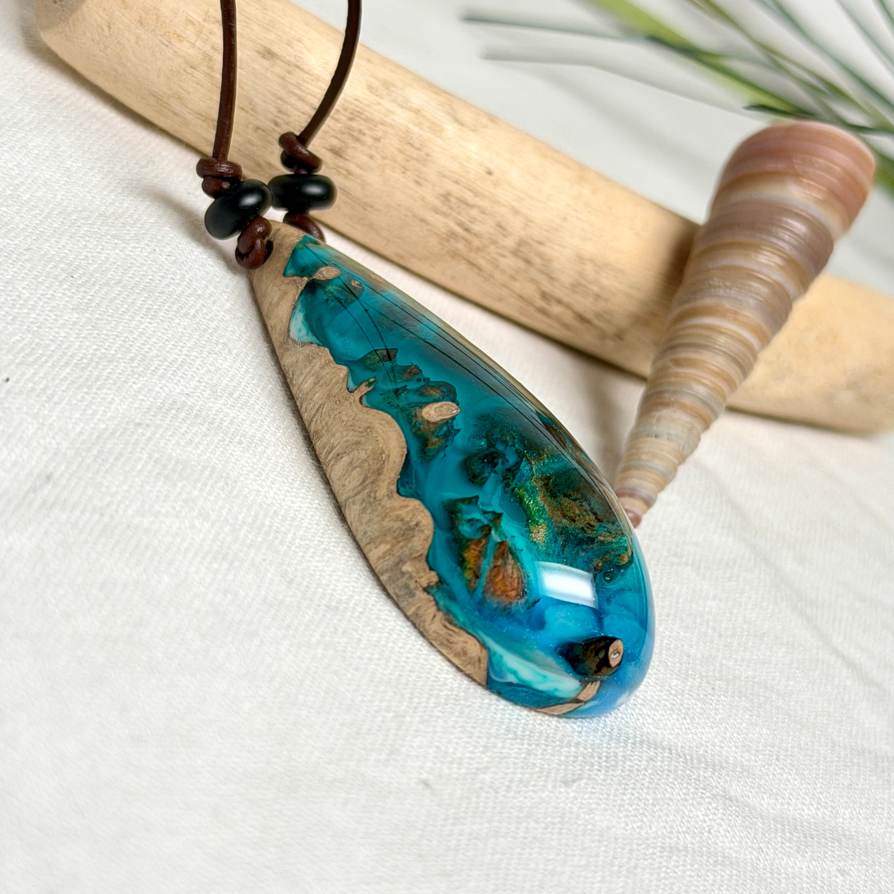 Holz-Harz-Anhänger aus Maserholz mit türkis-blauem Epoxidharz in Tropfenform am verstellbaren Lederband mit Onyxperlen, handgemachter maritimer Naturschmuck