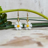 Handgefertigte Gänseblümchen-Ohrringe aus Harz mit 925 vergoldeten Ohrhaken, weiße Blüte mit gelbem Zentrum, goldfarbene Details, Länge ca. 4,5 cm.