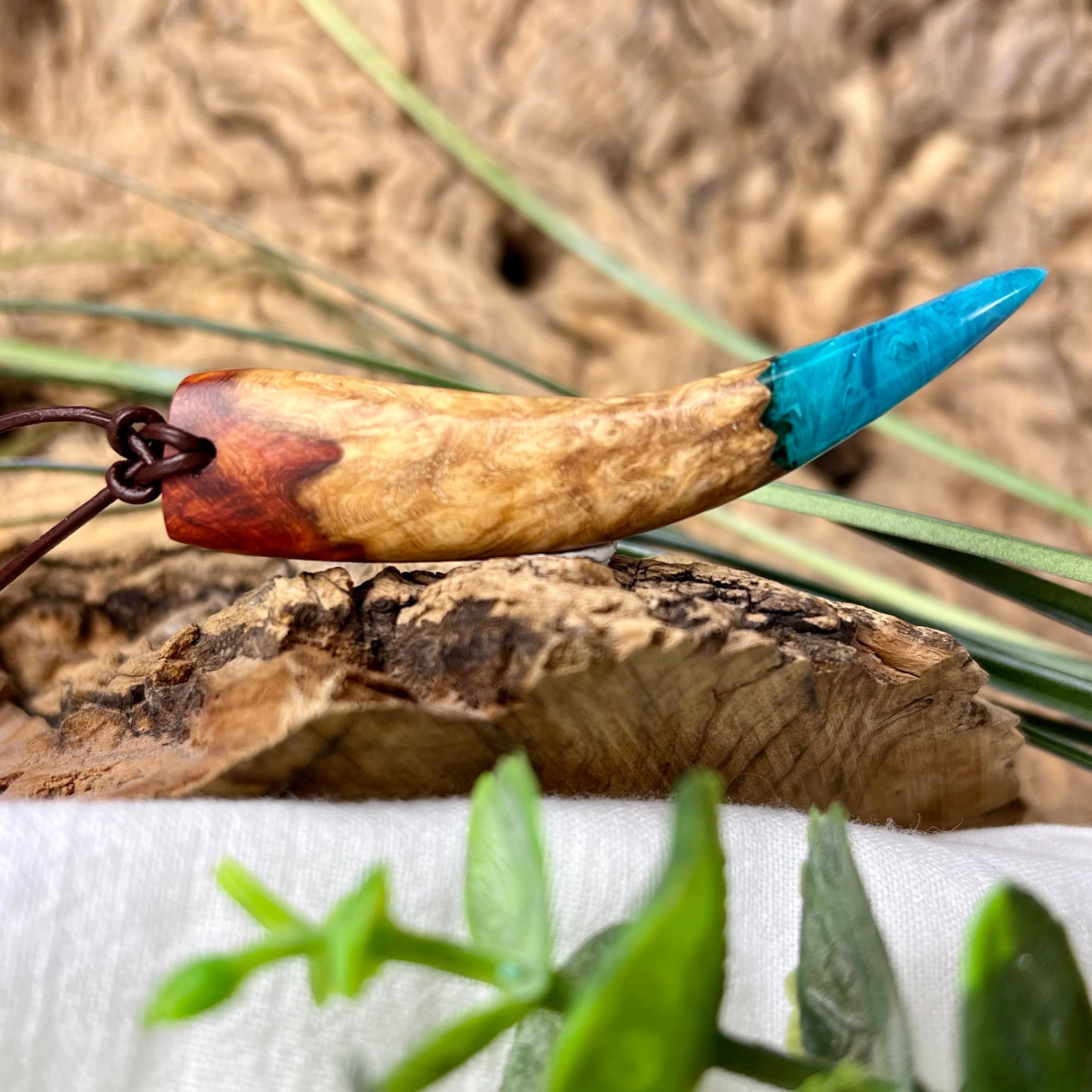 Handgefertigter Holzanhänger aus Amboniamaser-Holz mit leuchtendem blauem Epoxidharz an Lederband